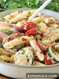 creamy pasta primavera in a bowl with a fork, with fresh parsley in the background