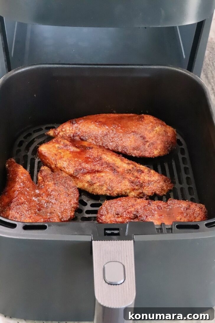 cooked chipotle honey chicken breasts in a an air fryer basket