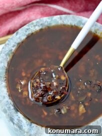 Calabrian chili crisp in a gray bowl with a white and gold spoon dipped in the sauce