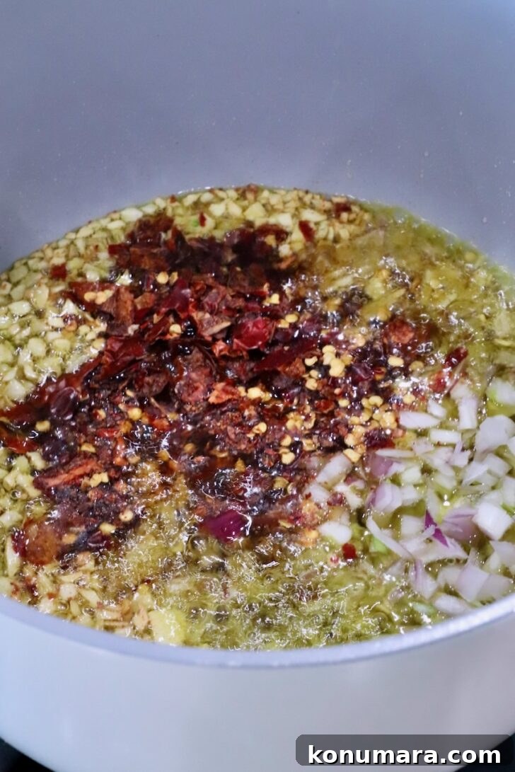 pot filled with oil, garlic, shallots, and chopped dried chilies on the stove