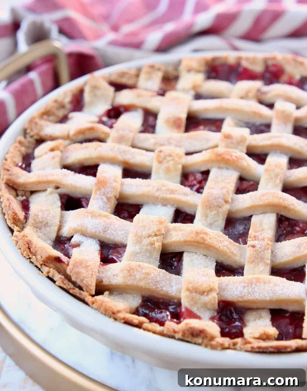 cherry pie with lattice crust in pie plate on marble serving tray