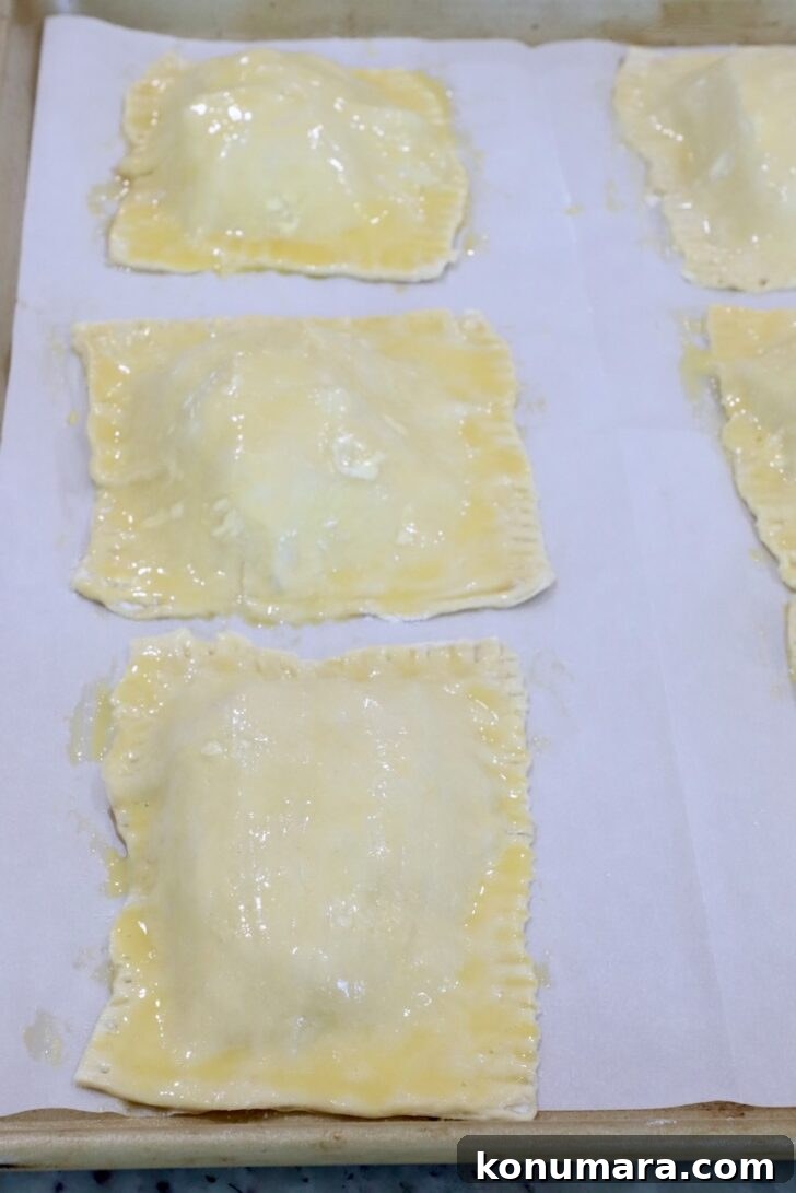 unbaked tarts on a parchment-lined baking sheet brushed with egg wash