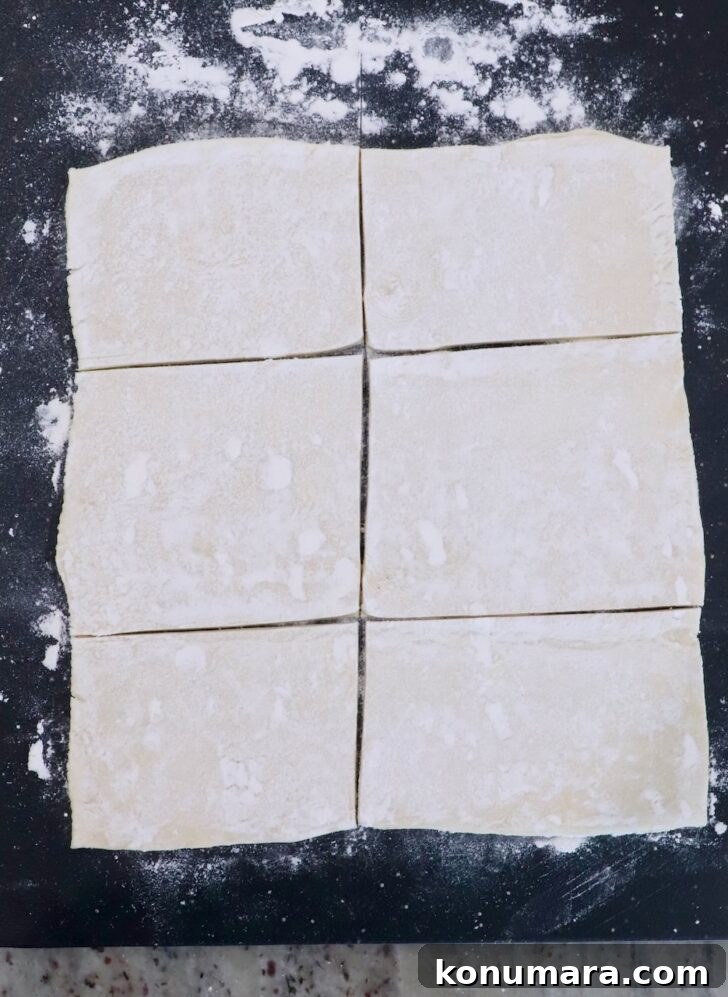 sheet of puff pastry dough cut into 6 rectangles on a dark cutting board