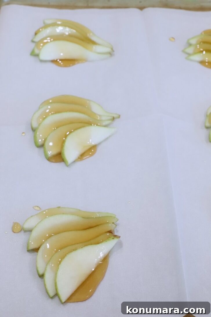 sliced pears topped with honey on a sheet of parchment paper on a baking sheet