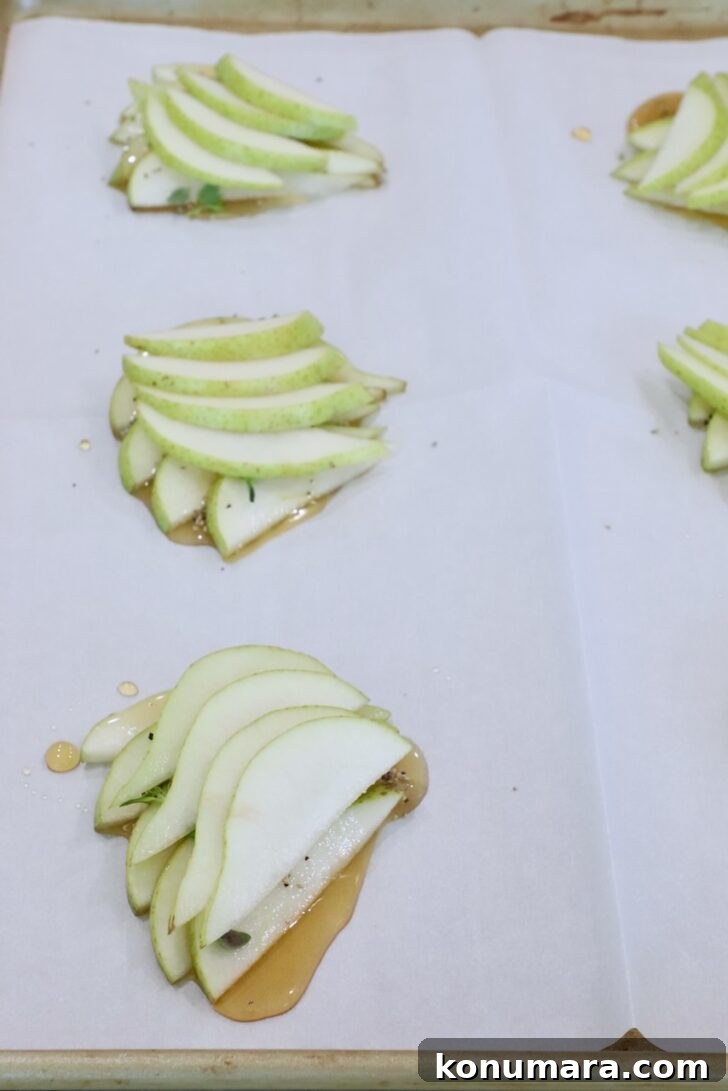 sliced pears stacked up  on a parchment-lined baking sheet