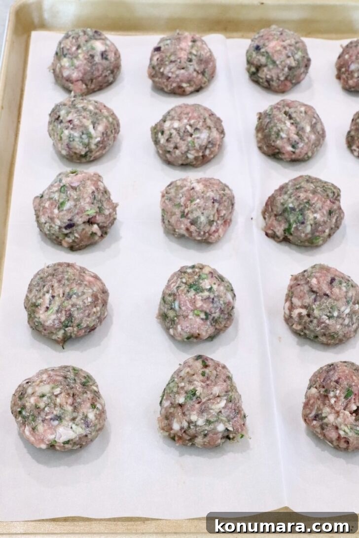 Gyro-Style Meatballs with Tzatziki Sauce 9 Raw meatballs arranged in rows on a parchment-lined baking sheet.