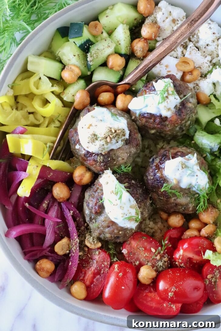 Gyro-Style Meatballs with Tzatziki Sauce 10 bowl filled with gyro meatballs topped with tzatziki sauce, surrounded by cucumbers, tomatoes, pickled onions, and chickpeas