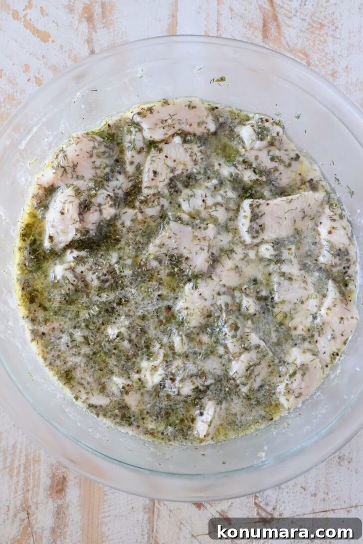 How to Make Authentic Greek Souvlaki 6 cubes of raw chicken in a lemon herb marinade in a glass bowl