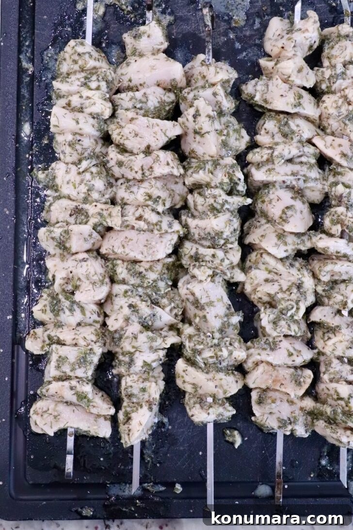 How to Make Authentic Greek Souvlaki 7 skewered cubes of marinated chicken on a black cutting board