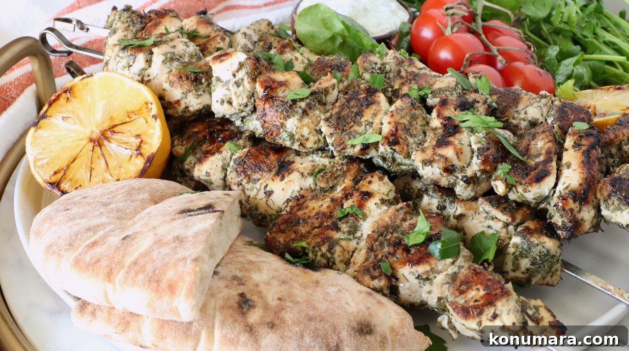 How to Make Authentic Greek Souvlaki 10 grilled chicken skewers on a plate with pita bread, grilled lemons, tomatoes and herbs