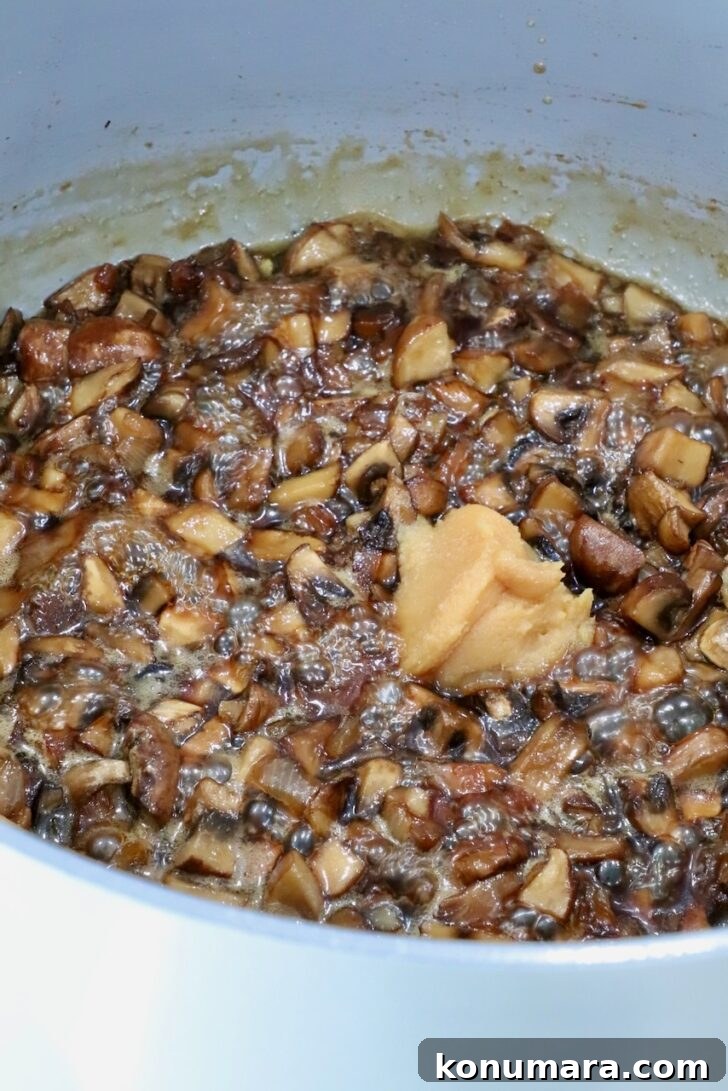 mushroom jam in a pot on the stove with a scoop of white miso paste