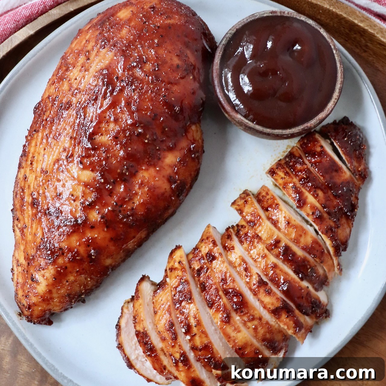 Smoked chicken breast sliced next to a small bowl of BBQ sauce
