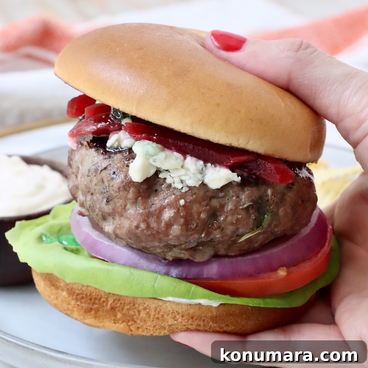 Hand holding a lamb burger on a bun