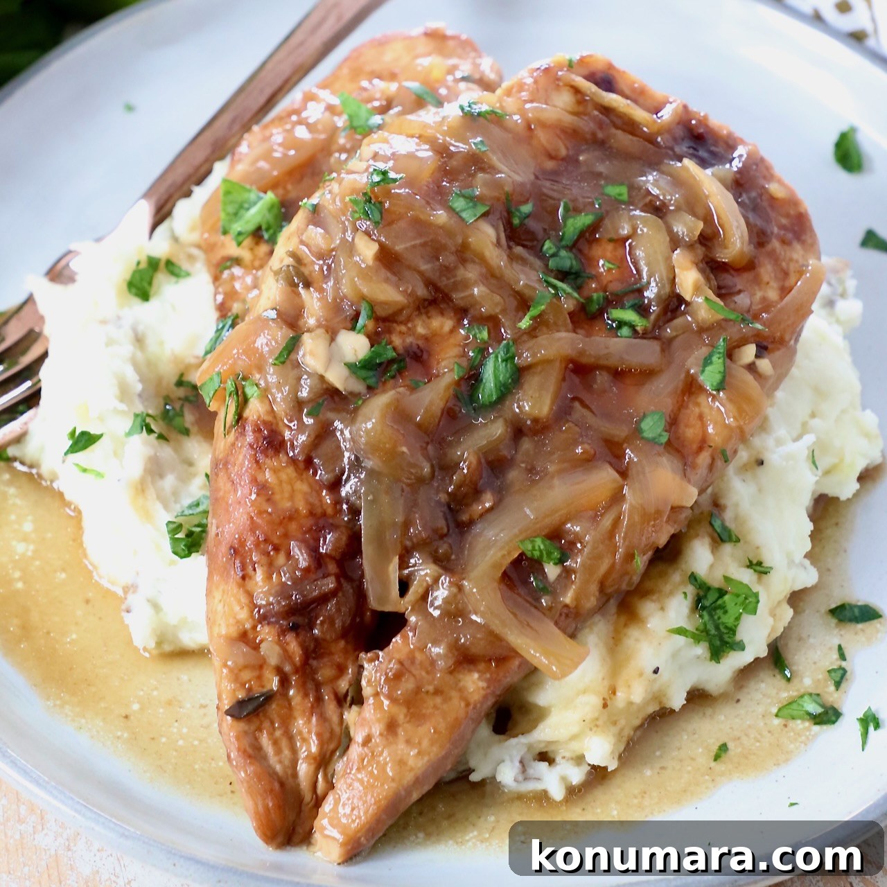 Cooked French onion chicken breasts on a plate with mashed potatoes