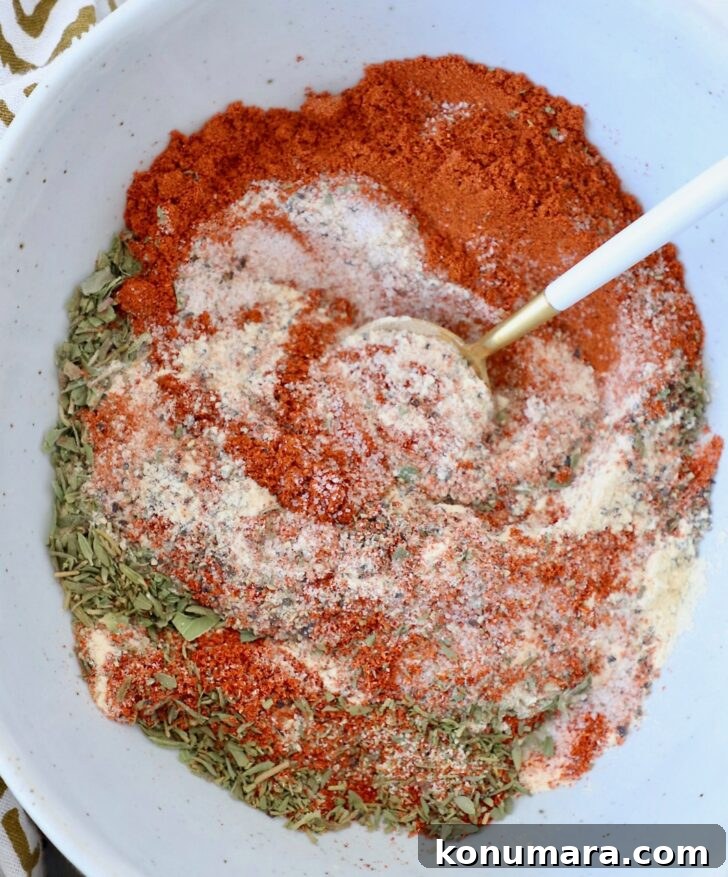 dried herbs and spices mixed together in a bowl with a spoon