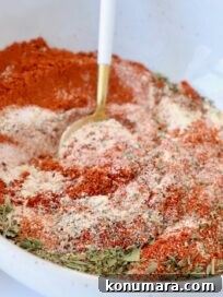dried herbs and spices combined in a bowl with a spoon