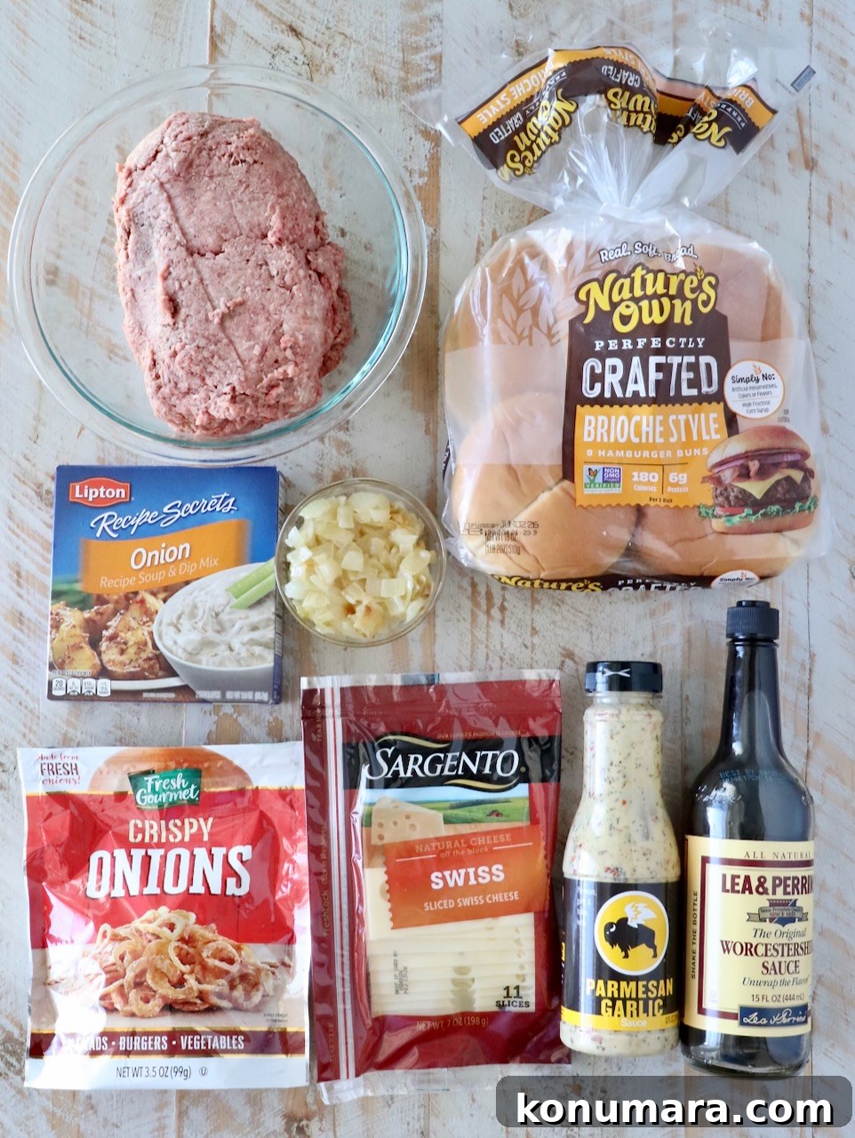 ingredients for french onion burgers on a white wood board