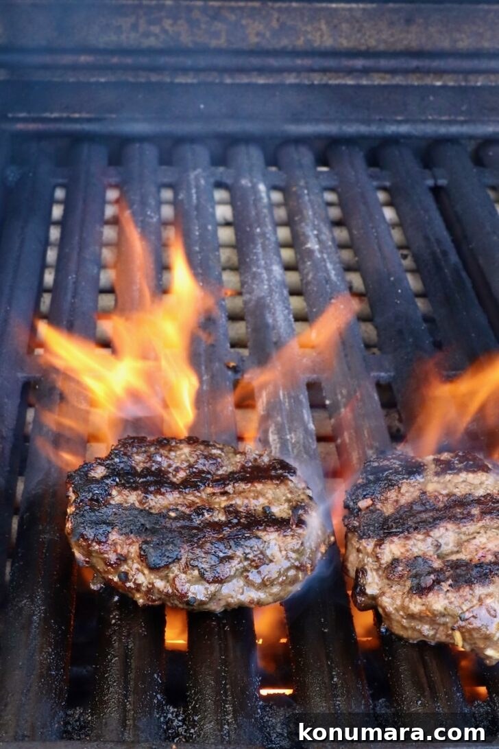 grilled burger patties on a grill with flames