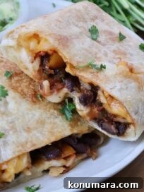 Vegetarian Cheesy Bean and Rice Burrito Recipe 17 bean and cheese burrito cut in half and stacked up on each other on a plate