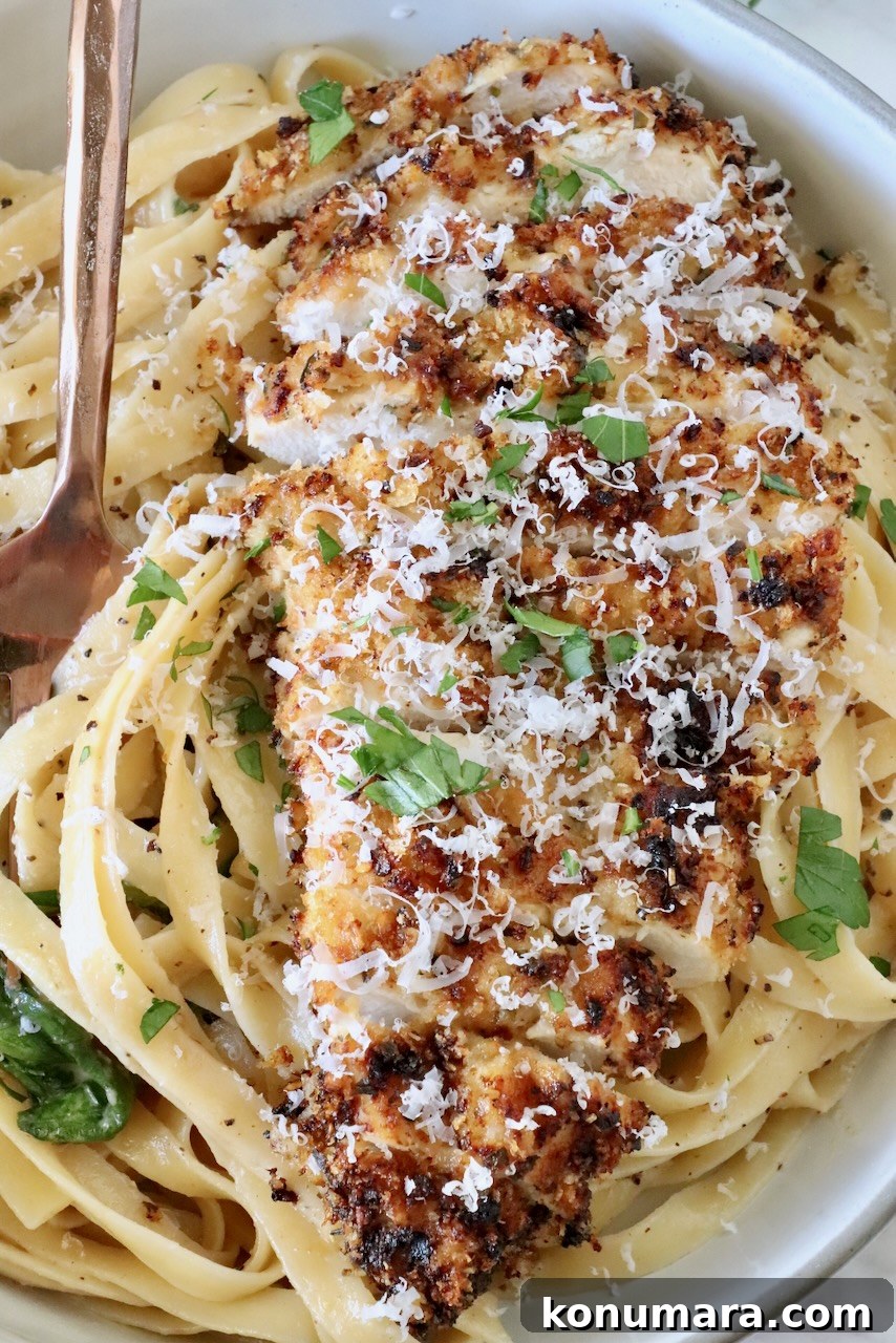 Creamy Chicken Caesar Pasta with Parmesan and Croutons 2 crispy sliced chicken on top of creamy noodles in a bowl with a fork