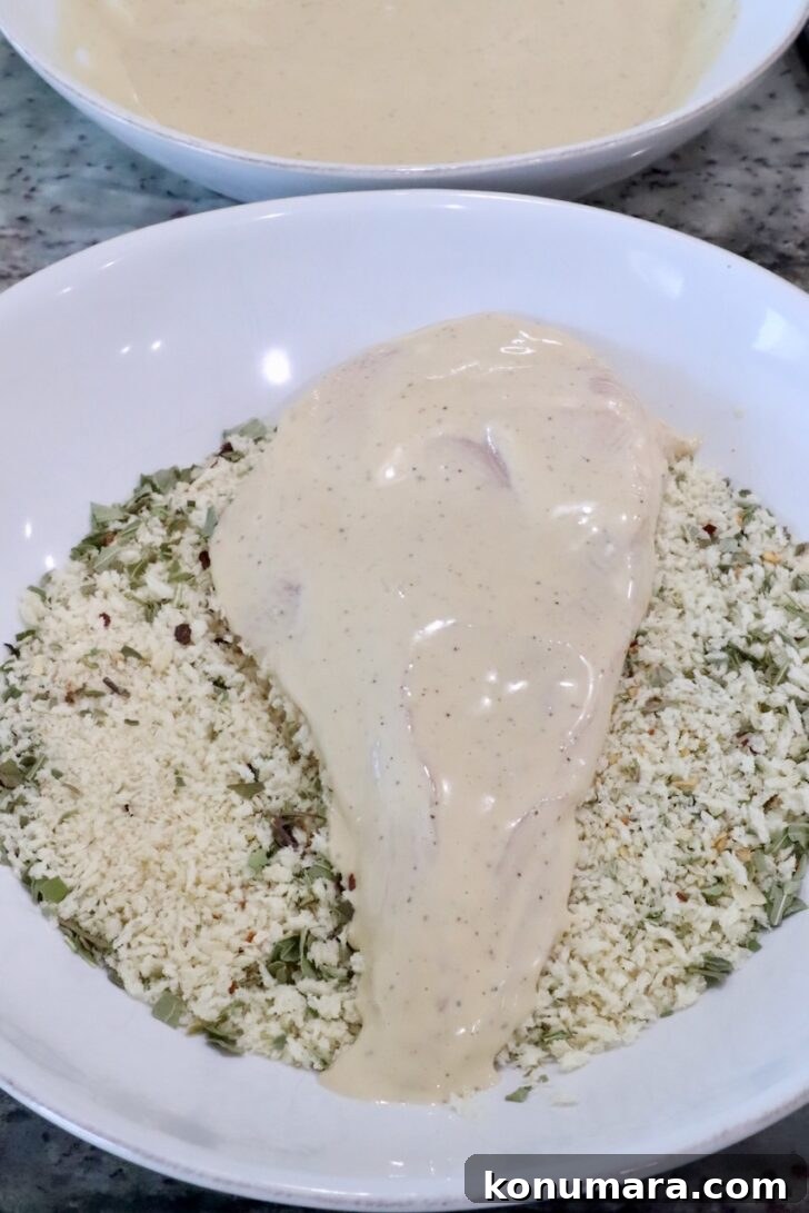 Creamy Chicken Caesar Pasta with Parmesan and Croutons 7 a chicken breast coated in caesar dressing in a bowl of Italian seasoned breadcrumbs