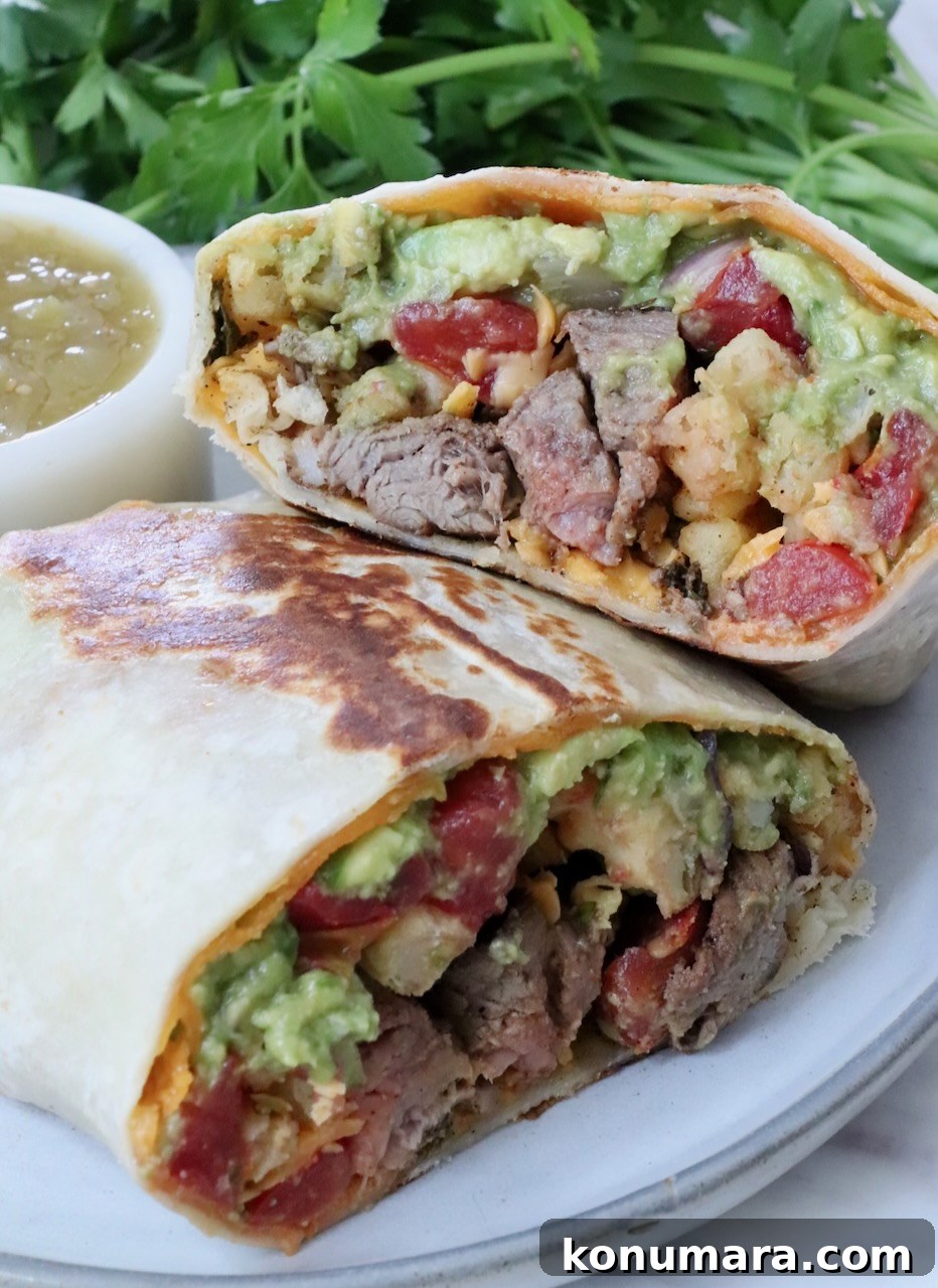 California burrito with carne asada and french fries cut in half and stacked up on a plate with a small bowl of salsa and fresh cilantro in the background