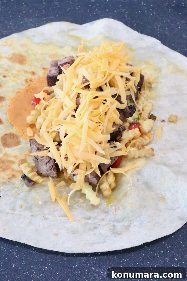 shredded cheese on top of carne asada in the middle of a tortilla