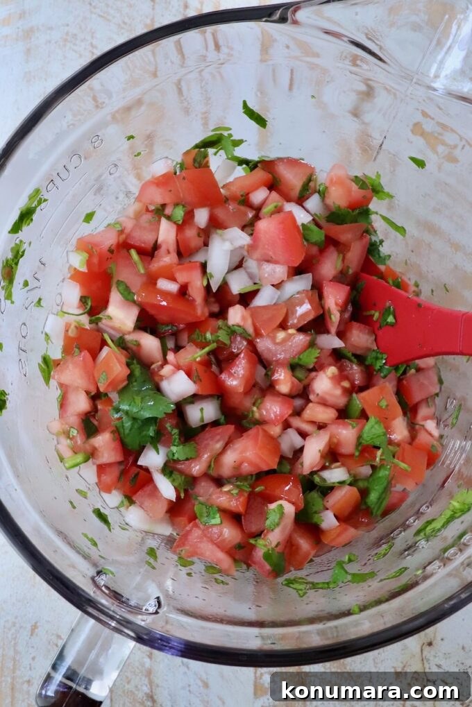 pico de gallo in a glass bowl with a red spatula