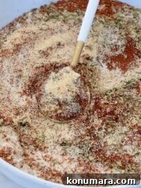 dried herbs and spices mixed together in a bowl with a spoon