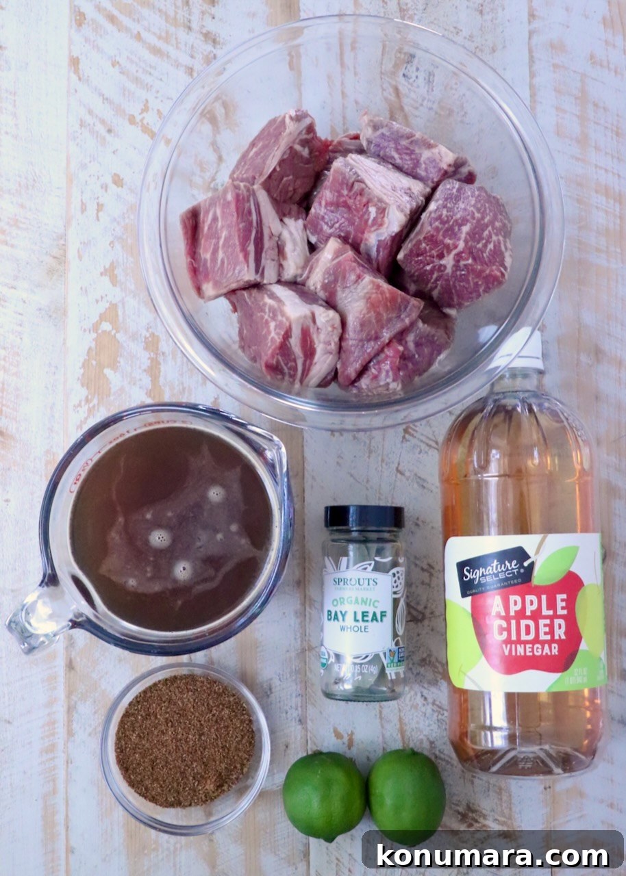 ingredients for beef barbacoa on a white wood board
