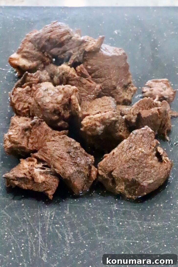 cooked chunks of beef on a cutting board
