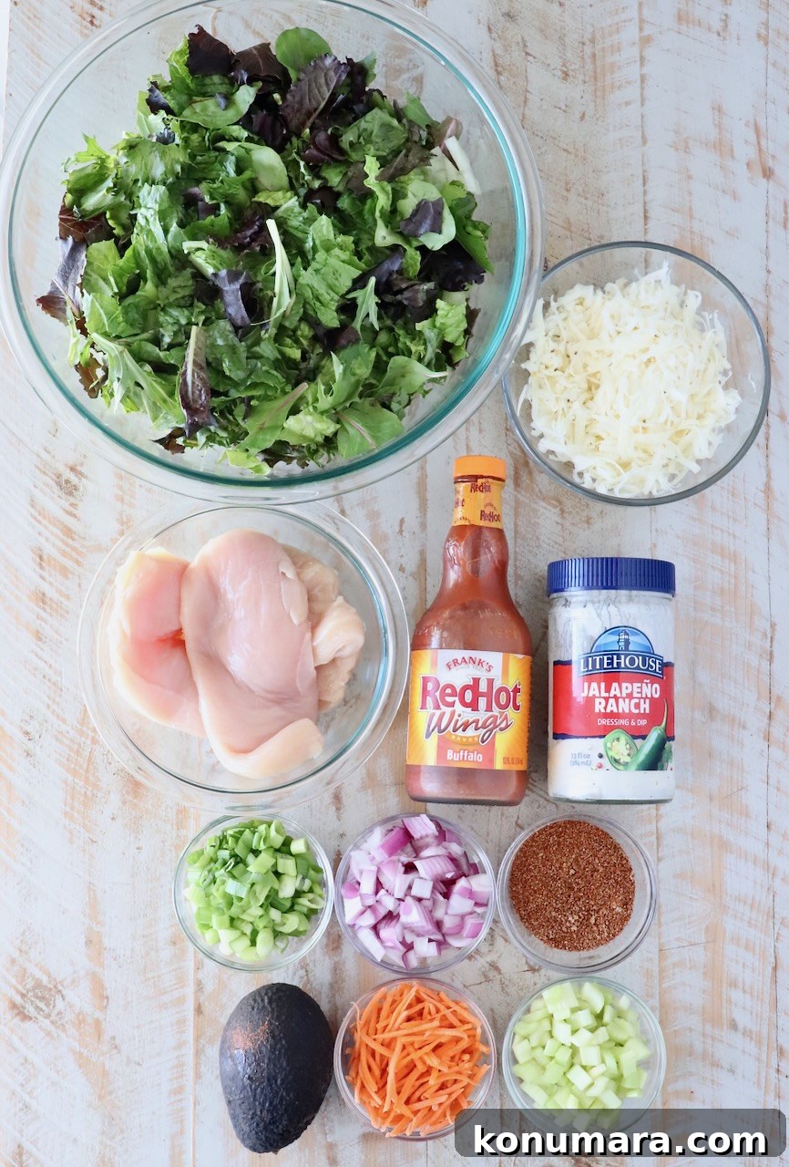 ingredients for a buffalo chicken salad on a white wood board
