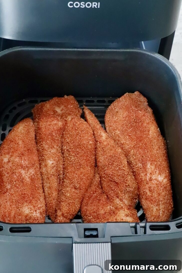 seasoned chicken breasts in an air fryer basket