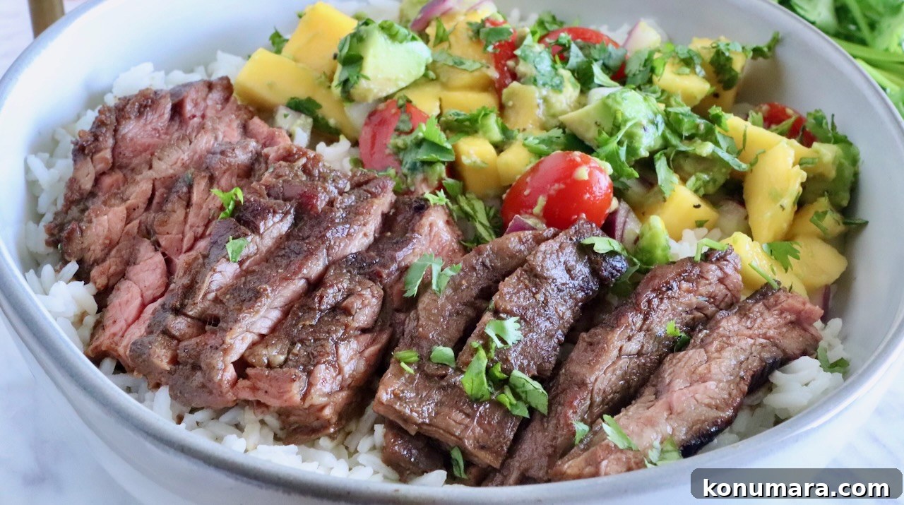 sliced steak in a bowl on top of rice with mango avocado salsa