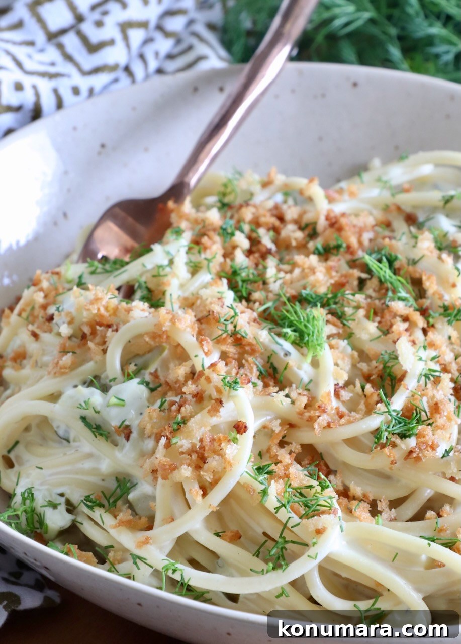 Creamy Dill Pickle Pasta Recipe 2 spaghetti tossed in a creamy sauce in a bowl topped with crunchy breadcrumbs and fresh dill