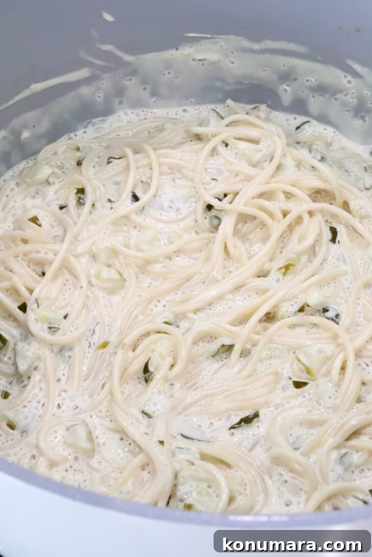 Creamy Dill Pickle Pasta Recipe 7 cooking spaghetti noodles in a creamy pickle sauce in a large pot