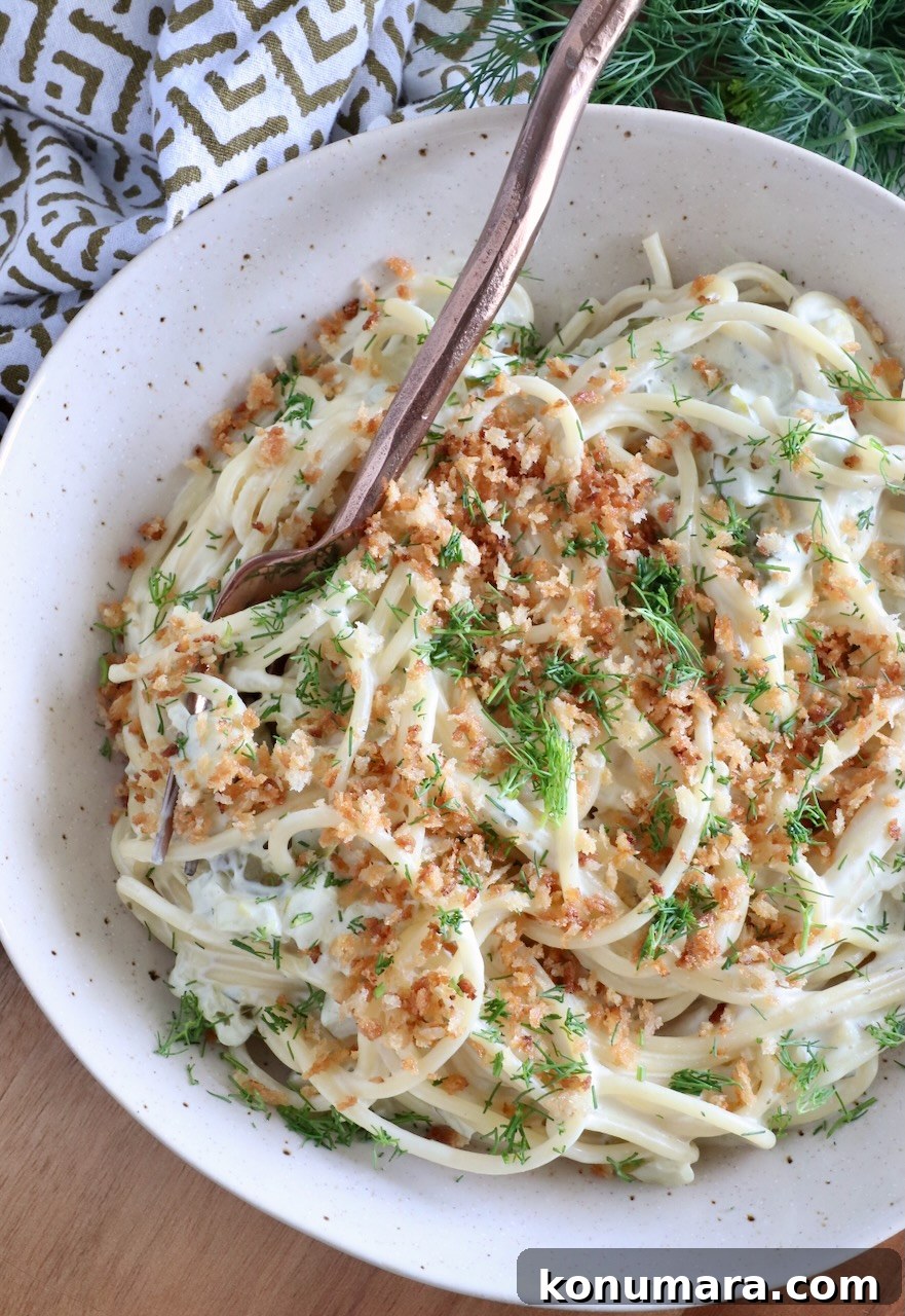 Creamy Dill Pickle Pasta Recipe 9 spaghetti tossed in a creamy sauce topped with breadcrumbs and dill in a bowl with a fork