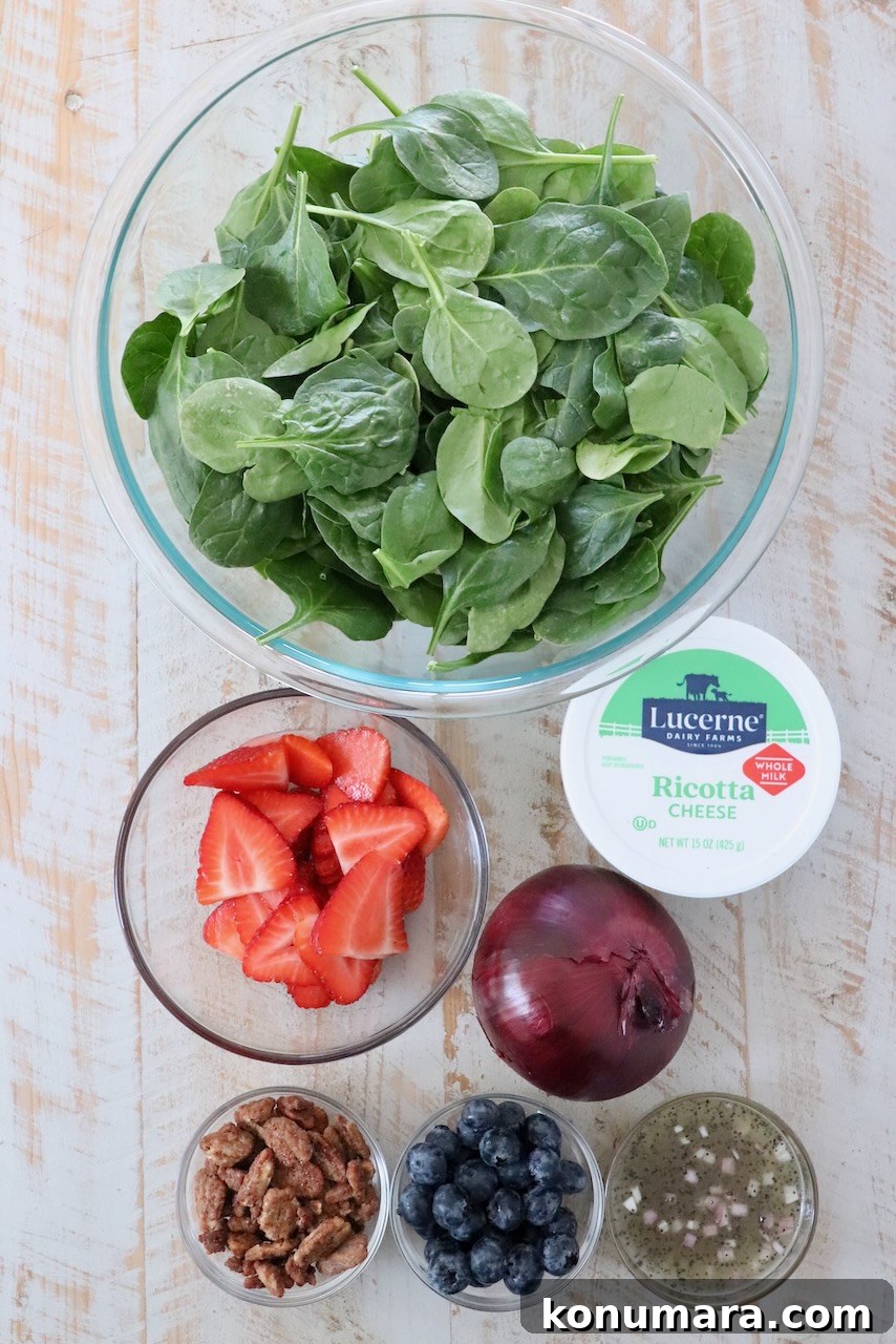 ingredients for spinach strawberry salad on white wood board