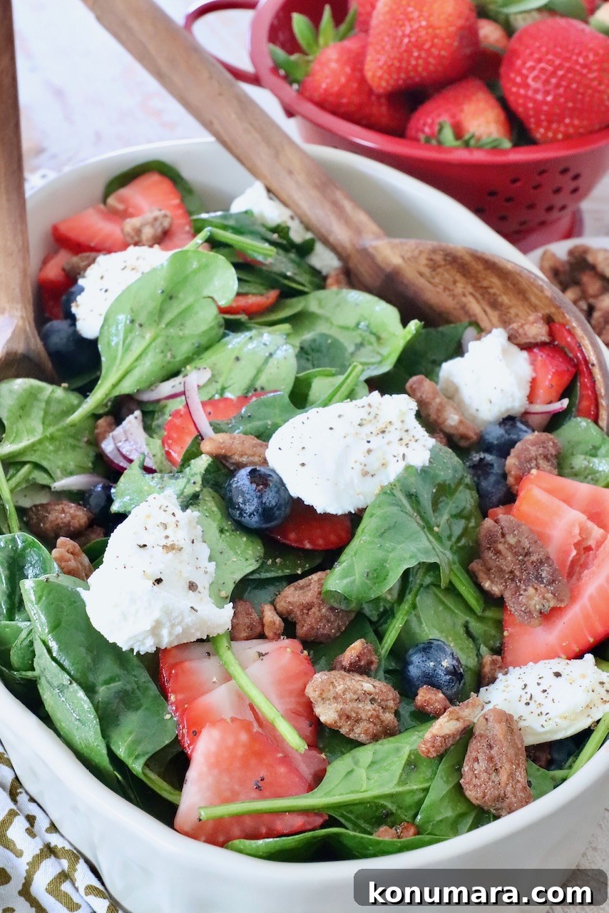 salad in large serving bowl topped with ricotta cheese, pecans and strawberries
