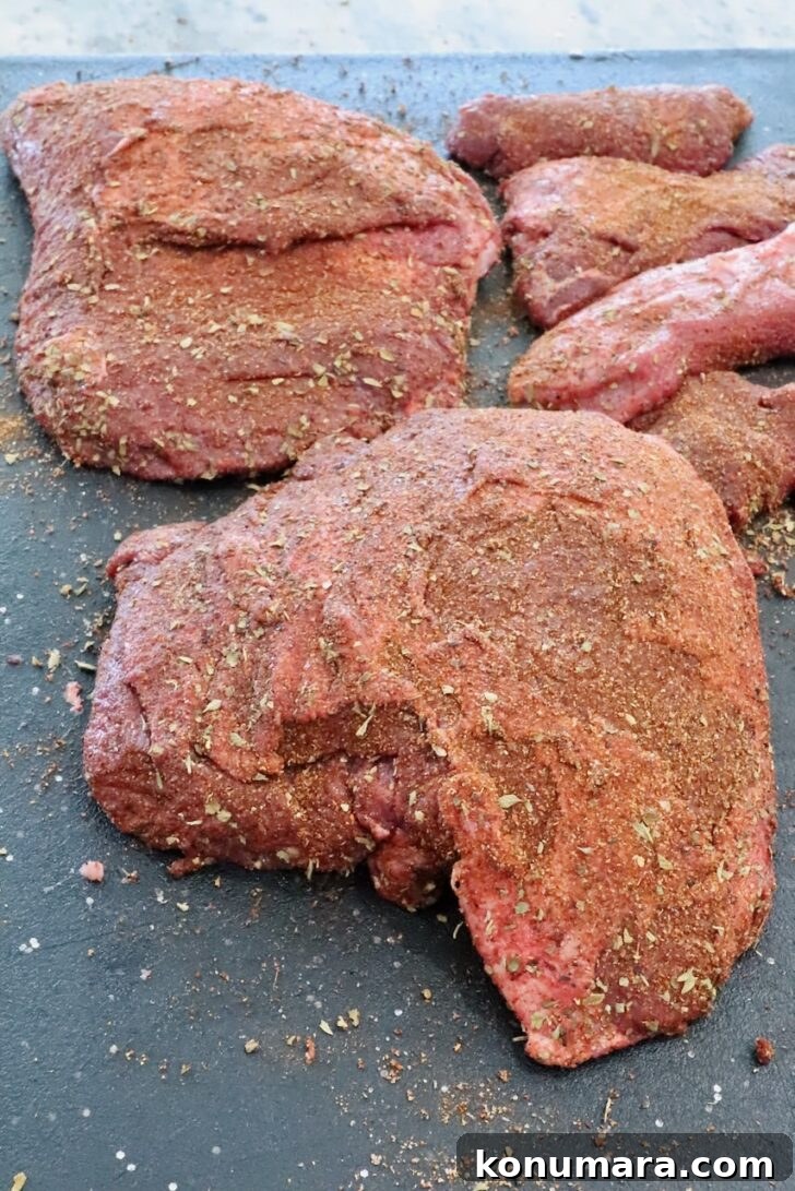 seasoned beef cheeks on a black cutting board