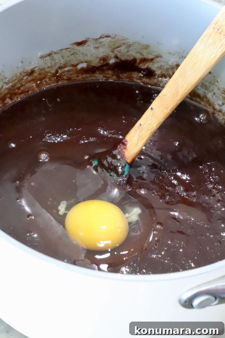 brownie batter topped with an egg in a pot with a spatula