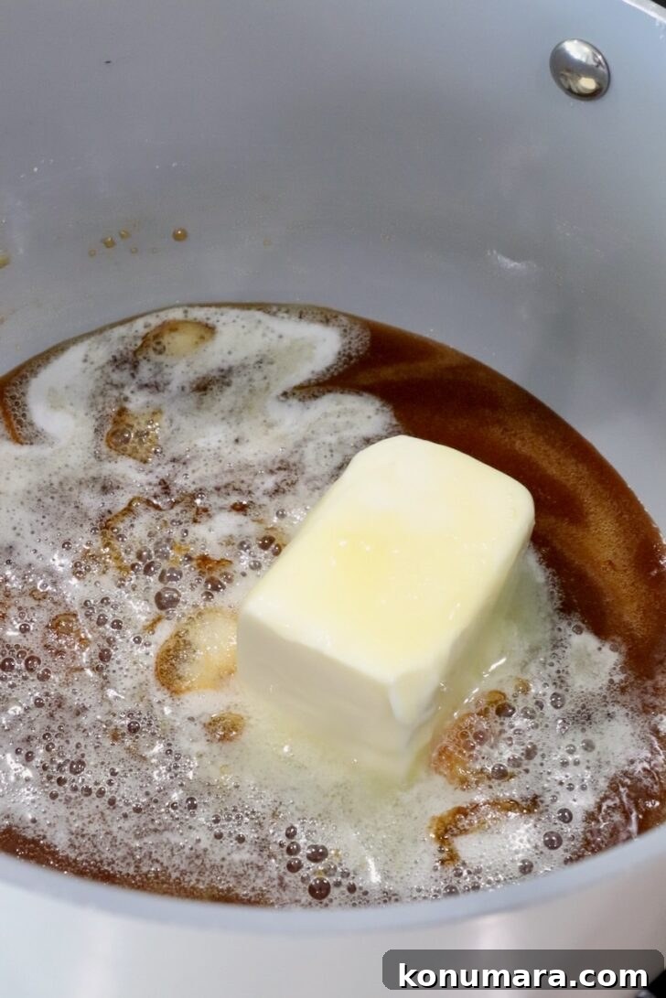 a stick of butter melting in a pot of caramel sauce