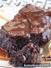 brownie on a plate covered in caramel sauce with a gold fork