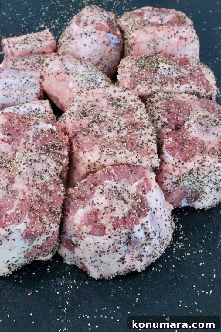 seasoned pieces of oxtail on a black cutting board