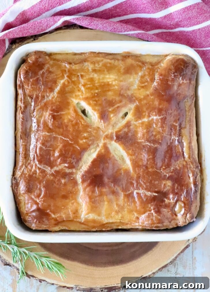 Braised Short Rib Pot Pie with French Onion 18 baked pot pie in a square baking dish on a wood serving tray with fresh herbs and a red and white striped towel