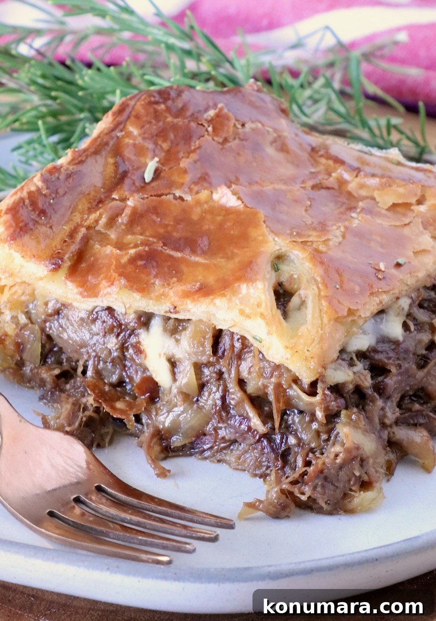Braised Short Rib Pot Pie with French Onion 25 slice of french onion short rib pot pie on a plate with a fork with fresh herbs in the background