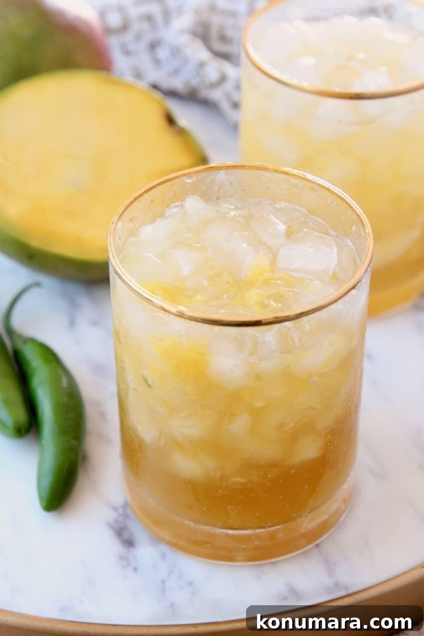 Mango margaritas in glasses on marble tray with fresh mango sliced open
