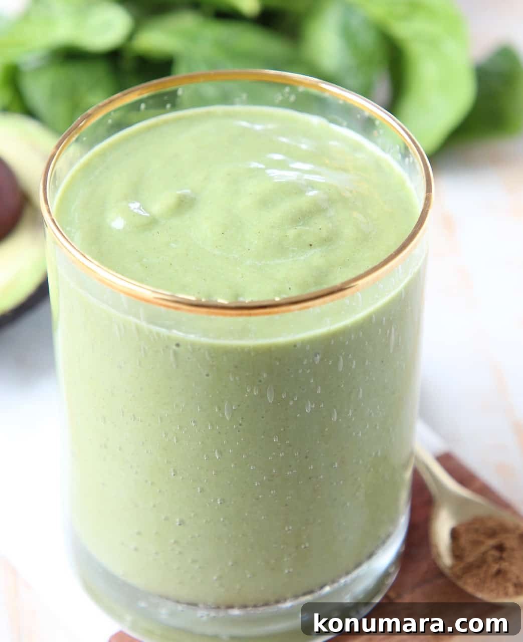 Superfood Green Smoothie Recipe with Spinach and Avocado 3 Green smoothie in glass sitting in front of fresh spinach and an avocado