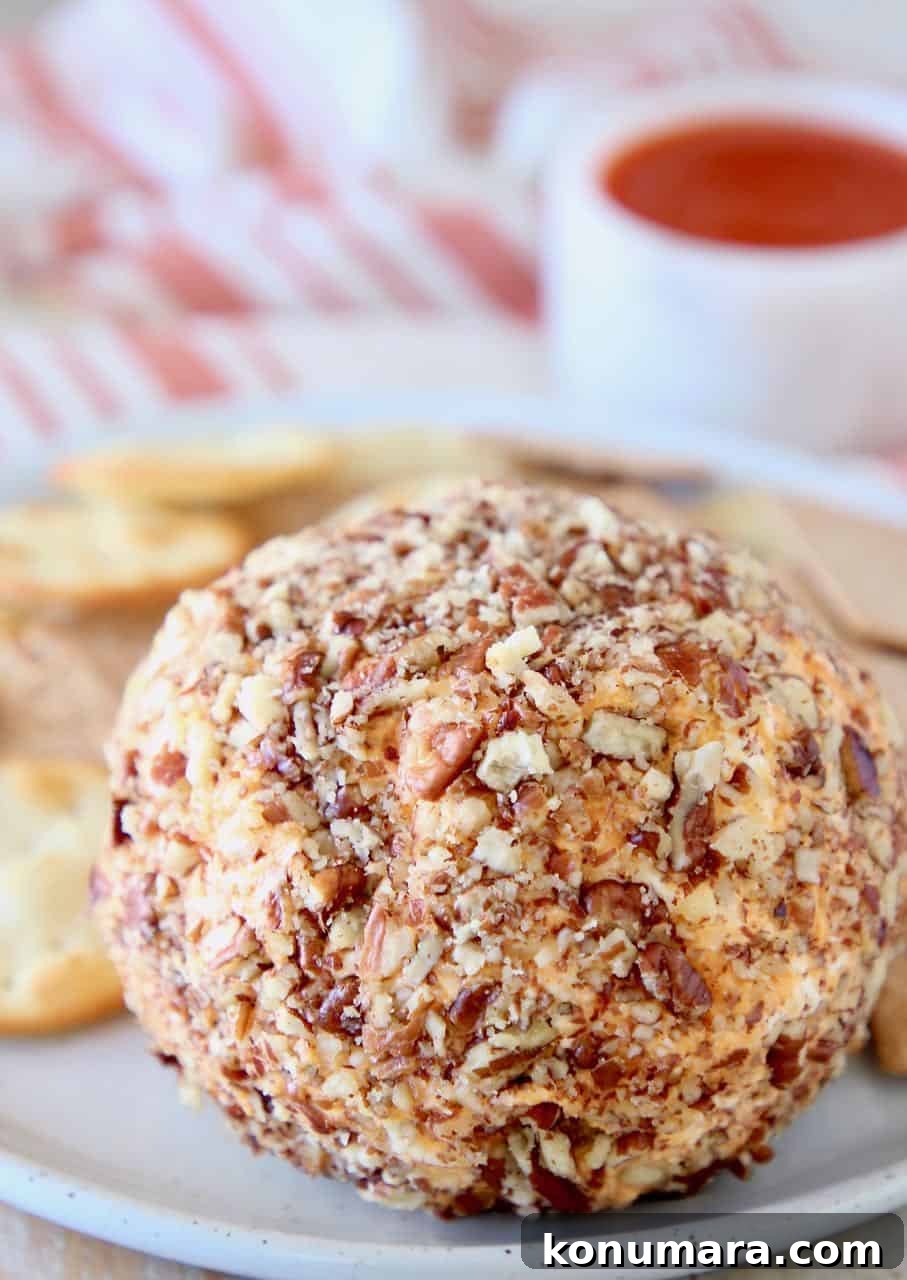 Buffalo cream cheese ball rolled in pecans on plate with crackers