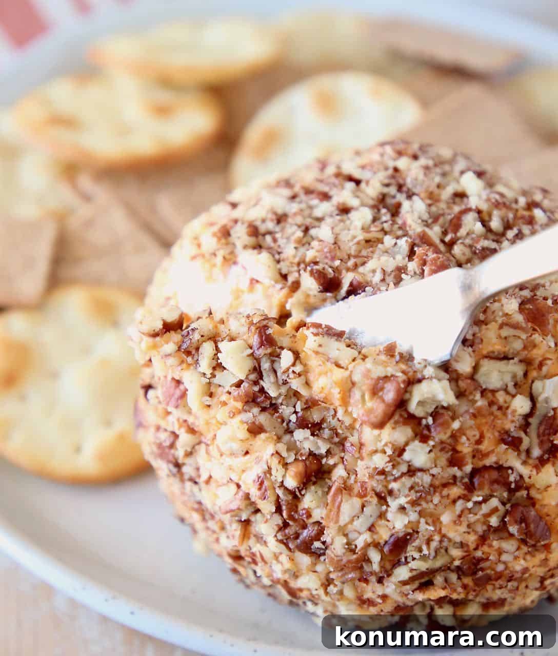 Buffalo cream cheese ball being sliced into with cheese knife
